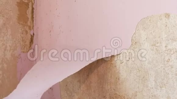 家庭维修雄手用特制的刮刀从墙上剥去粉红色的旧墙纸视频的预览图