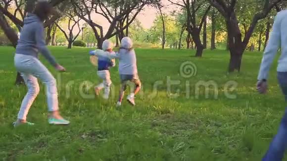 父母和两个女儿在盛开的花园里的春天公园里玩球积极的休闲视频的预览图