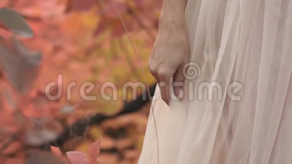 穿着白色衣服站在树叶背景下的女人的手视频的预览图