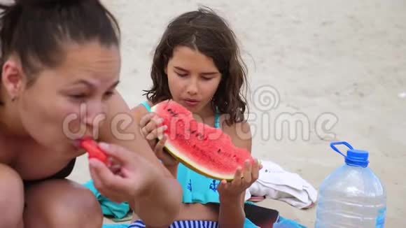 孩子们青少年在海滩上休息笑着吃西瓜慢动作视频少女休息视频的预览图