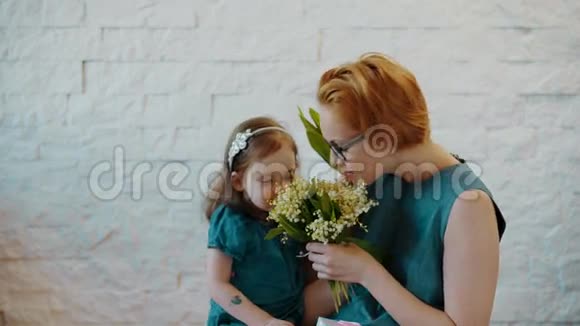 妈妈和小女儿闻着美丽的花朵视频的预览图