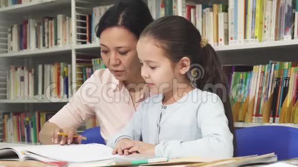 可爱的小女孩和她妈妈一起做作业视频的预览图