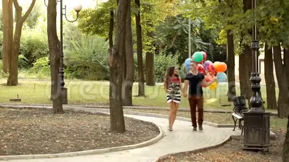 一对爱着气球的年轻夫妇在公园里漫步视频的预览图