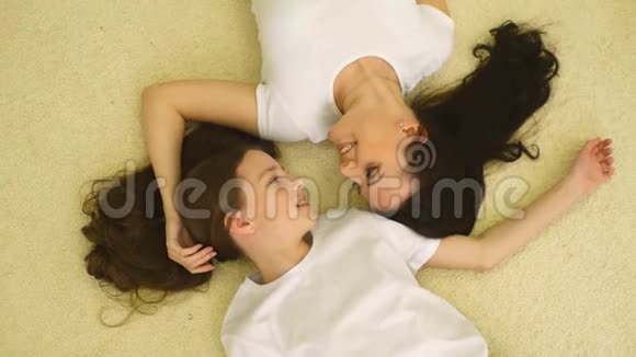妈妈和穿着冬天睡衣的小女儿在床上放松和玩耍视频的预览图