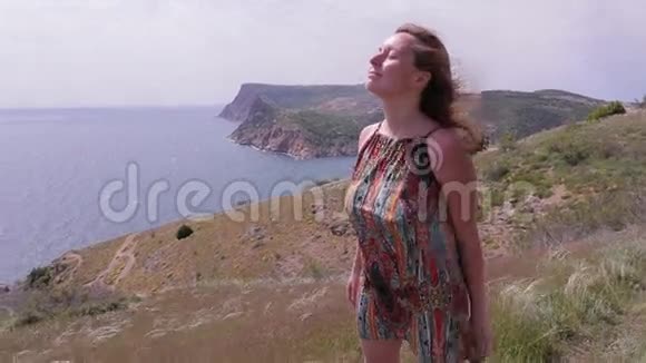 女人站在海边的山上刮风的日子视频的预览图