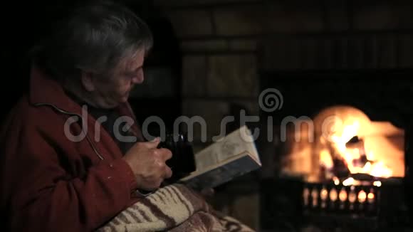 老人拿着书坐在壁炉边喝茶视频的预览图