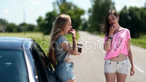在汽车附近吃和喝咖啡的年轻女性视频的预览图