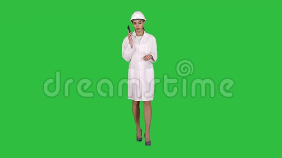 女工程师在绿色屏幕上行走时打电话Chroma键视频的预览图