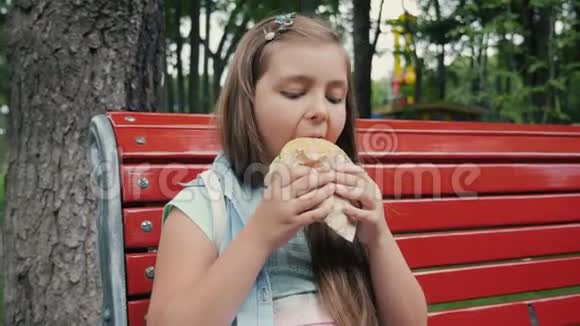在公园里吃汉堡的小女孩视频的预览图