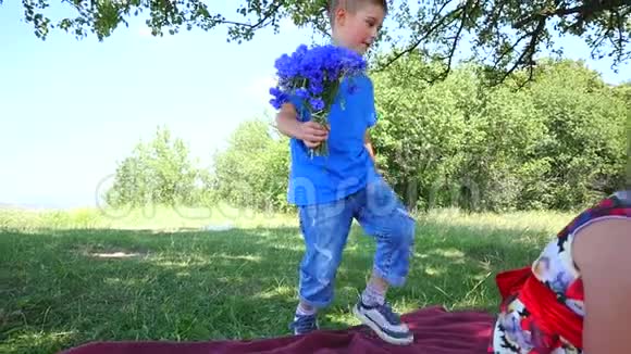 男孩正在给漂亮的女孩送花恋爱中的年轻夫妇阳光公园里两个可爱的孩子绿色的快乐视频的预览图
