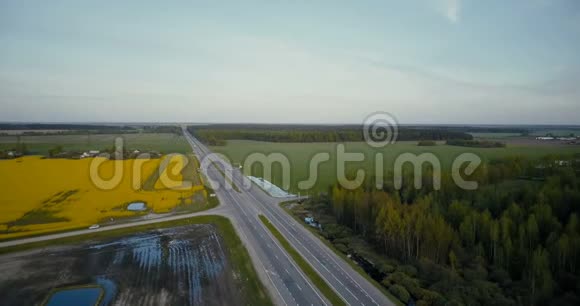 有森林和油菜花田的平坦地带的高速公路空中无人机4K旋转射击农作物产业物流视频的预览图