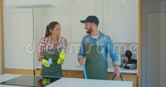 一对夫妇的肖像作为一名职业清洁工穿着制服站在一起在室内使用清洁工具视频的预览图