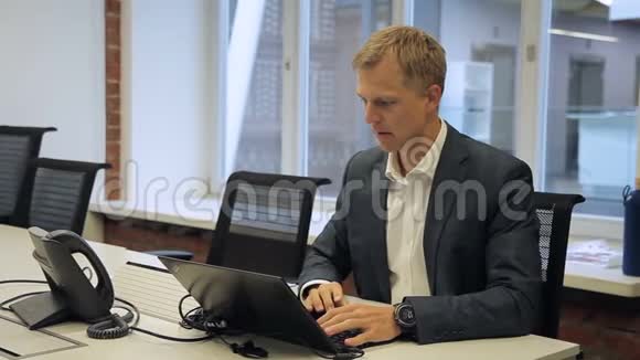 男头正在办公桌上工作笔记本电脑坐在现代办公室里视频的预览图