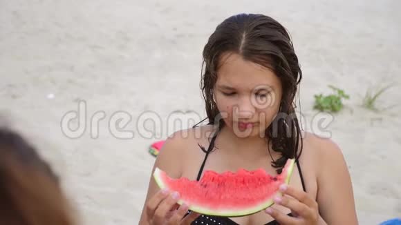 孩子们在海滩上吃西瓜青春痘少女吃西瓜慢动作视频生活方式视频的预览图
