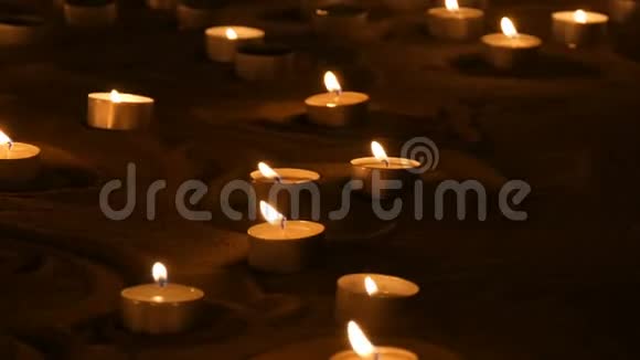 大量白色的小圆蜡烛在沙子里燃烧蜡烛燃烧的背景视频的预览图