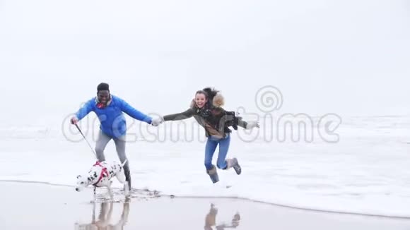 年轻夫妇在冬季海滩躲避海浪视频的预览图