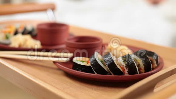 女人端着托盘和美味的日本寿司卷上床睡觉视频的预览图