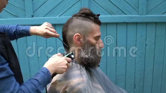 女理发师理发师男理发师头发电动剃须刀理发师为留胡子的男子梳头视频的预览图