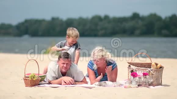 年轻的一家人在河岸享受周末视频的预览图