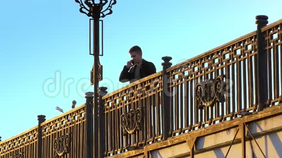 年轻人走在桥上打电话聊日落视频的预览图