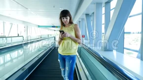 站在自动人行道上的女人站在地铁口的楼梯上用她的电话一种交流的手段一种时尚视频的预览图