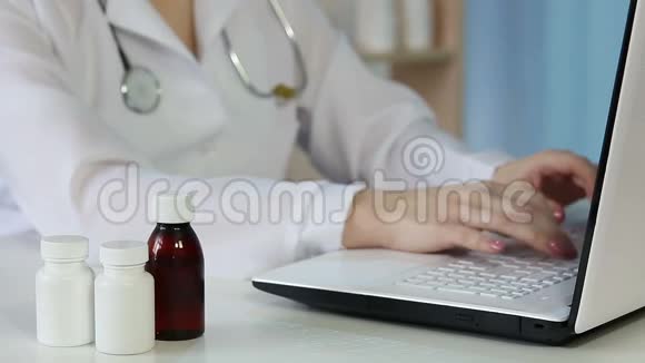 穿着白大褂的女医生检查药瓶上的信息在笔记本电脑上打字视频的预览图