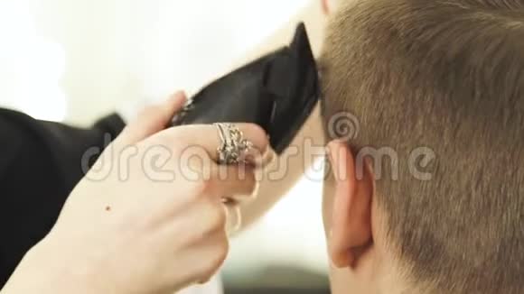 理发店里用电动剃须刀剪头发女理发师和客户一起做男理发师视频的预览图
