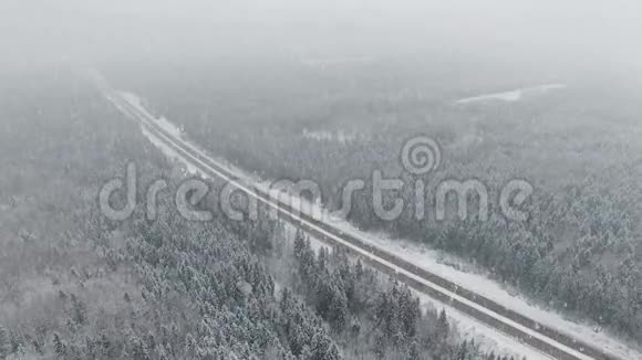 4K道路在冬季森林与驾驶汽车在降雪空中全景消失的视角视频的预览图
