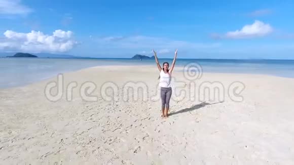 空中年轻美丽的混合种族女孩在桑迪海滩向太阳瑜伽问好泰国范甘高清慢速运动视频的预览图
