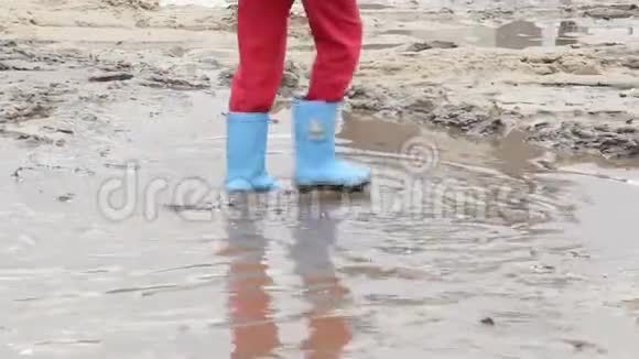儿童的脚踩在泥坑上穿蓝色靴子儿童不安全视频的预览图