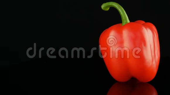 美丽的大熟红色甜椒辣椒在镜面和黑色背景上旋转视频的预览图