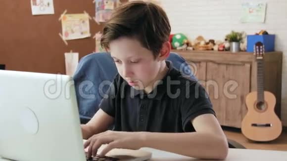 可爱的小男孩在他的笔记本电脑键盘上打字视频的预览图