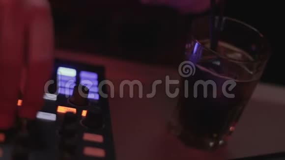 DJ站在音频调音台上按下和转动按钮鸡尾酒玻璃视频的预览图