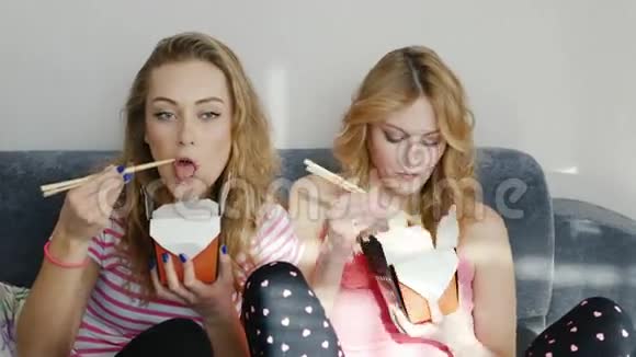 两个年轻的女朋友一起看一部有趣的电影吃木筷纸袋视频的预览图