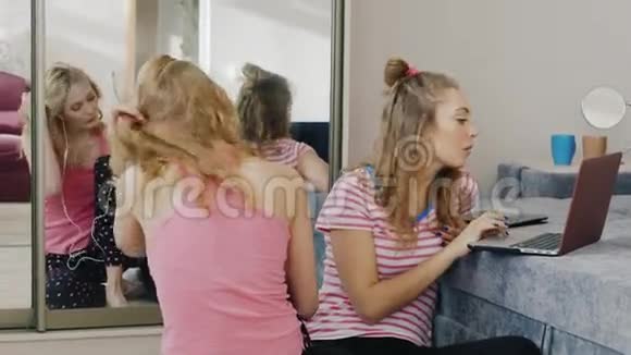 两位年轻女性在家放松使用不同的设备电话笔记本电脑帕贾玛派对女友视频的预览图