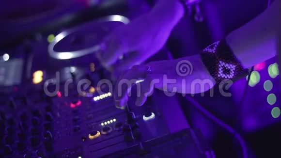男DJ拿着控制台按钮在流行的夜总会里播放音乐视频的预览图