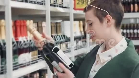 年轻女子选择了一瓶香槟然后放进购物车视频的预览图
