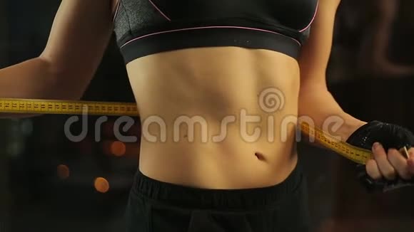 女人展示她平坦的腹部和健康的身体用胶带测量腰部视频的预览图