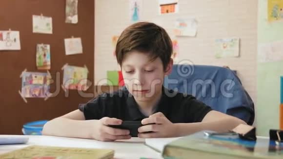 可爱的小男孩在智能手机上玩电脑游戏视频的预览图