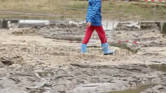 穿靴子的孩子走在泥坑上孩子们不安全的照顾视频的预览图