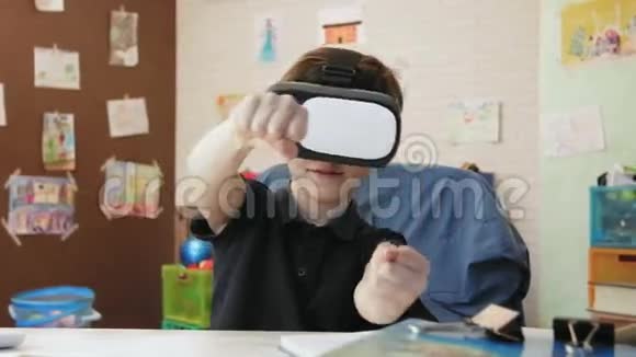 可爱的小男孩使用虚拟现实耳机玩赛车游戏视频的预览图