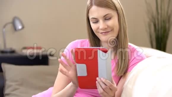 美丽迷人的年轻女子穿着粉红色的t恤通过信使与朋友交流视频的预览图