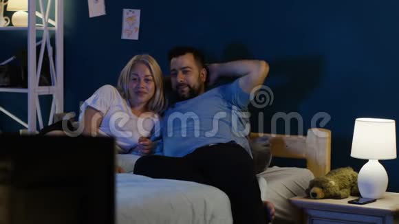 成年夫妇在床上看电视视频的预览图