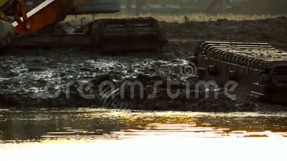 挖掘机铲斗在日落时从河底挖土渠道清理深化视频的预览图