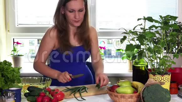 厨房里的孕妇用洋葱和有机蔬菜做新鲜沙拉视频的预览图