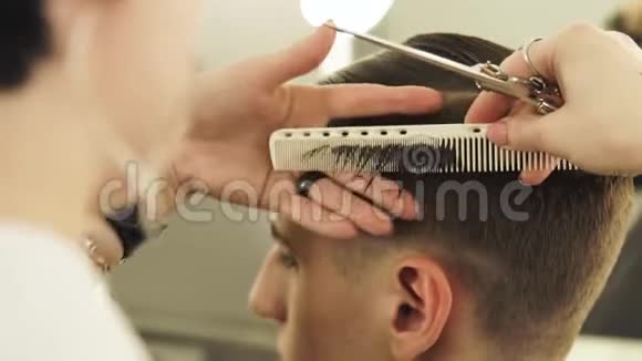 女理发师梳头剪用专业剪刀特写理发师用梳子做男性发型视频的预览图