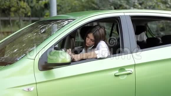 坐在车里的女孩在电话里谈生意在笔记本上做笔记视频的预览图