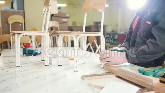 一家家具厂的工人木匠用电动螺丝刀拧椅子腿视频的预览图