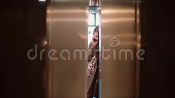 电梯门开着女人站在电梯里用手机说话然后离开了视频的预览图