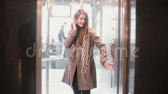 女人站在电梯里在智能手机上说话女性按下按钮门被关闭视频的预览图